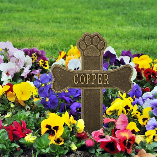 Dog Paw & Bone Memorial Cross in Antique in Brass in the Garden Surrounded by Colorful flowers